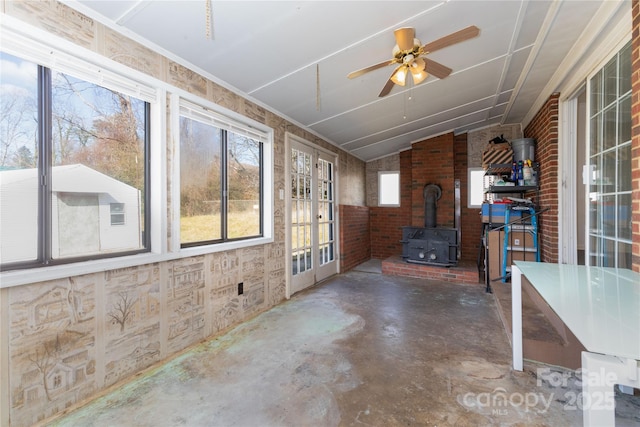 unfurnished sunroom with french doors, ceiling fan, vaulted ceiling, and a wood stove