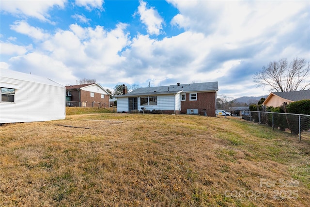 rear view of house with a mountain view and a yard