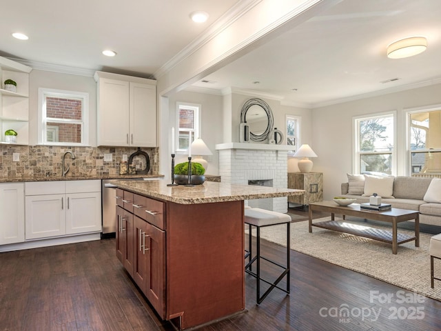 kitchen with white cabinetry, a center island, dark wood-type flooring, light stone counters, and sink