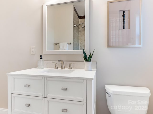 bathroom featuring toilet, vanity, and a tile shower