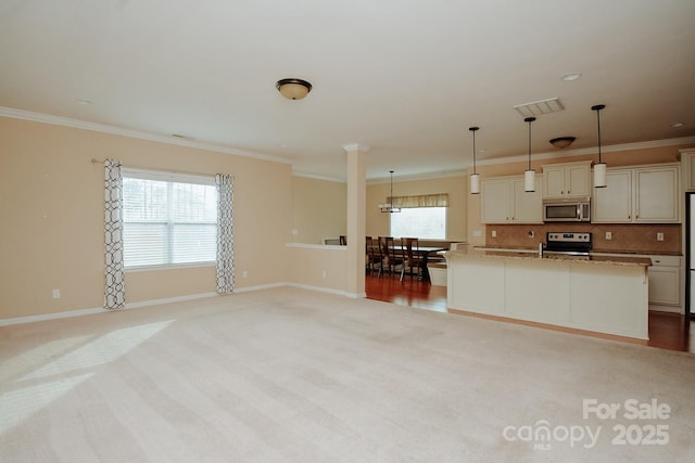 kitchen with pendant lighting, stainless steel appliances, a center island with sink, and ornamental molding