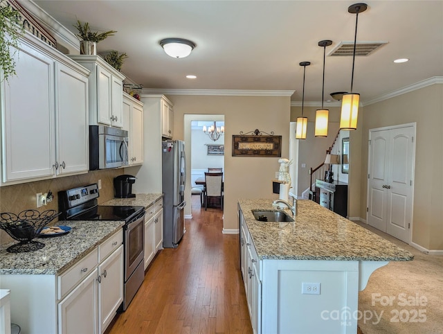 kitchen with pendant lighting, a center island with sink, sink, appliances with stainless steel finishes, and light stone counters