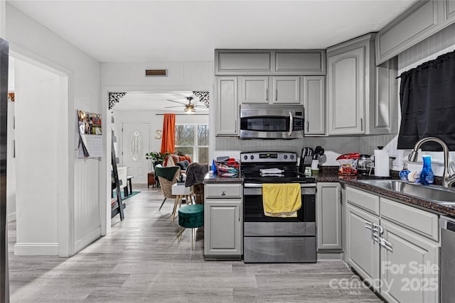 kitchen featuring gray cabinetry, ceiling fan, sink, stainless steel appliances, and light hardwood / wood-style flooring