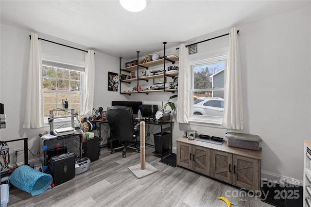 home office with a wealth of natural light and light hardwood / wood-style flooring