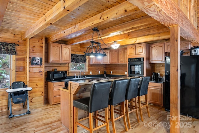 kitchen with wood walls, wooden ceiling, black appliances, and light wood-style floors