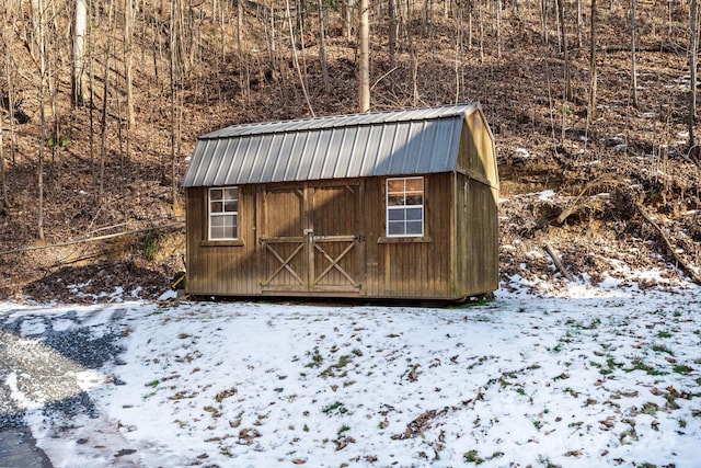 snow covered structure with a storage unit and an outbuilding