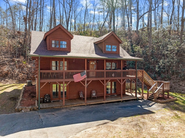 log-style house with a deck, stairway, central air condition unit, and a shingled roof