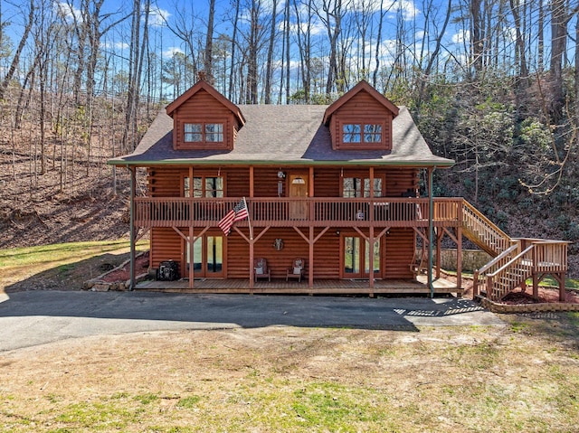 log-style house with log siding, roof with shingles, and a deck