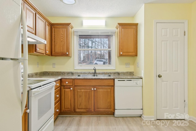 kitchen featuring a textured ceiling, light hardwood / wood-style floors, white appliances, and sink