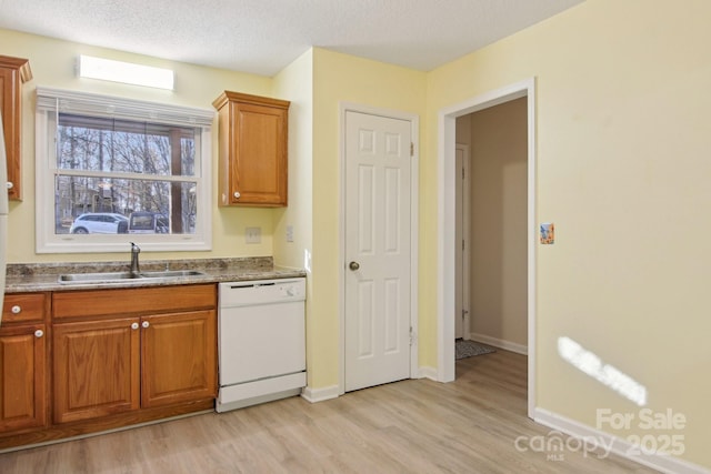 kitchen featuring dishwasher, light hardwood / wood-style floors, a textured ceiling, and sink