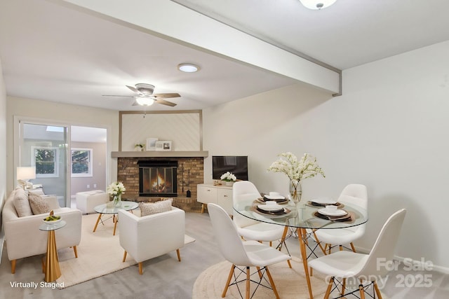 carpeted dining space with beamed ceiling, a brick fireplace, and ceiling fan