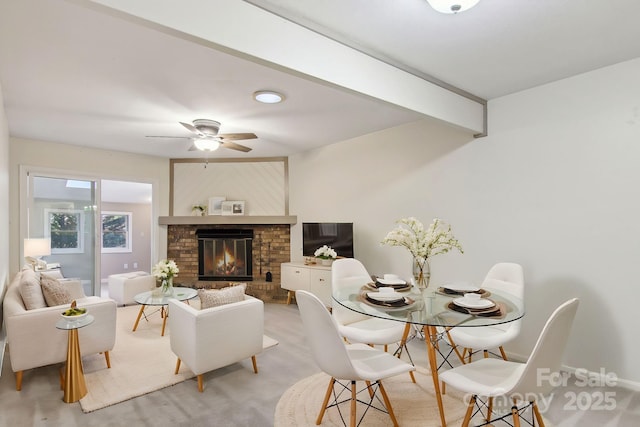 carpeted dining space featuring beamed ceiling, ceiling fan, and a brick fireplace