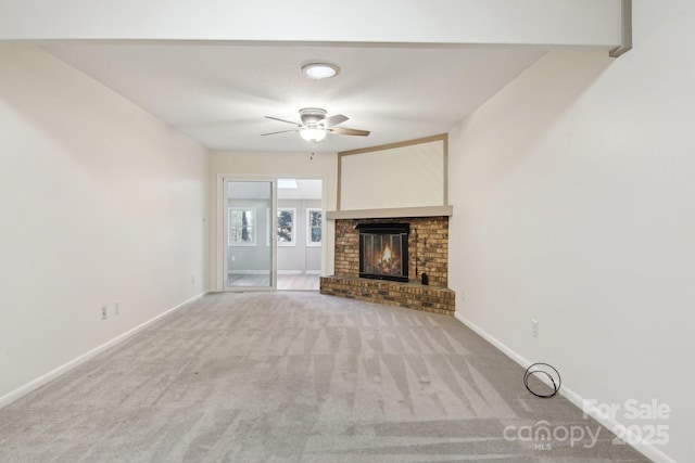 unfurnished living room featuring ceiling fan, light carpet, and a brick fireplace