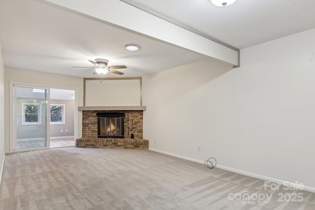 unfurnished living room featuring beam ceiling, ceiling fan, a fireplace, and a textured ceiling