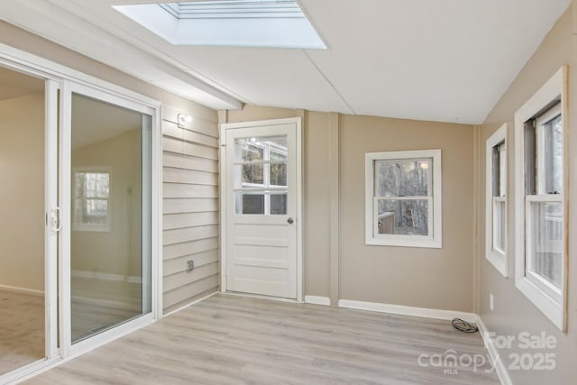 unfurnished sunroom with lofted ceiling with skylight