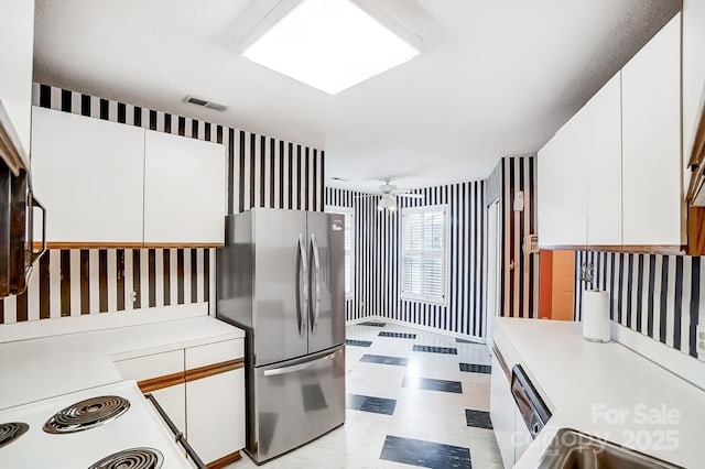 kitchen featuring ceiling fan, stainless steel fridge, and white cabinetry