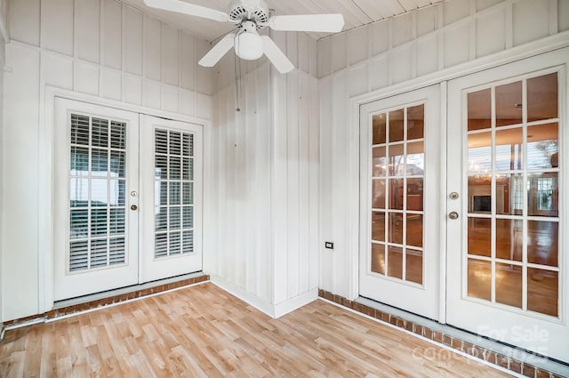 interior space featuring ceiling fan, wood walls, and french doors