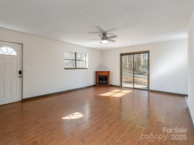 unfurnished living room with wood-type flooring, plenty of natural light, and ceiling fan