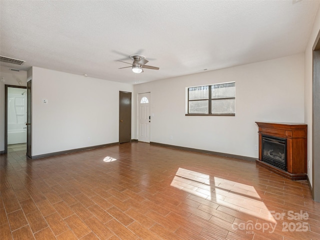 unfurnished living room featuring ceiling fan and a textured ceiling