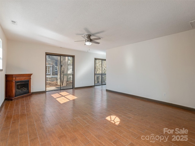 unfurnished living room featuring ceiling fan and a textured ceiling