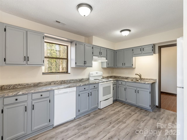 kitchen with a textured ceiling, sink, light hardwood / wood-style floors, and white appliances