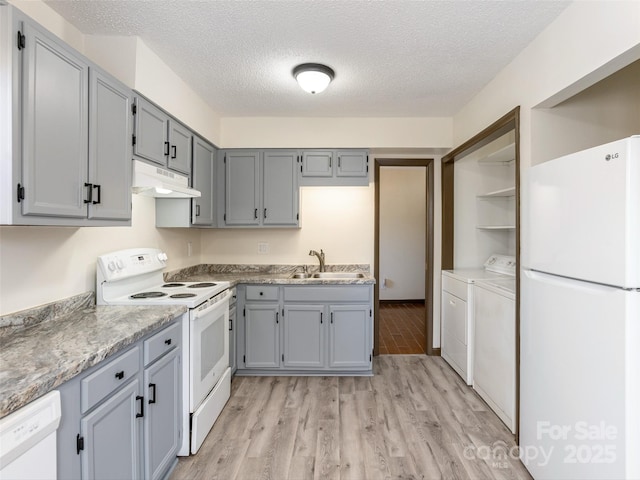 kitchen featuring washer and dryer, a textured ceiling, white appliances, and sink