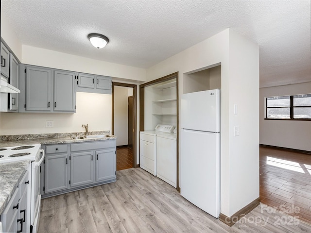 kitchen featuring washer and clothes dryer, white appliances, sink, light hardwood / wood-style flooring, and a textured ceiling