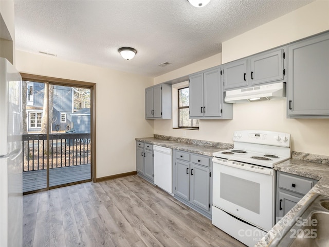 kitchen featuring gray cabinets, light wood-type flooring, white appliances, and a textured ceiling