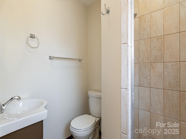 bathroom with a tile shower, vanity, and toilet