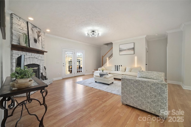 living area featuring a large fireplace, baseboards, stairway, ornamental molding, and light wood-type flooring