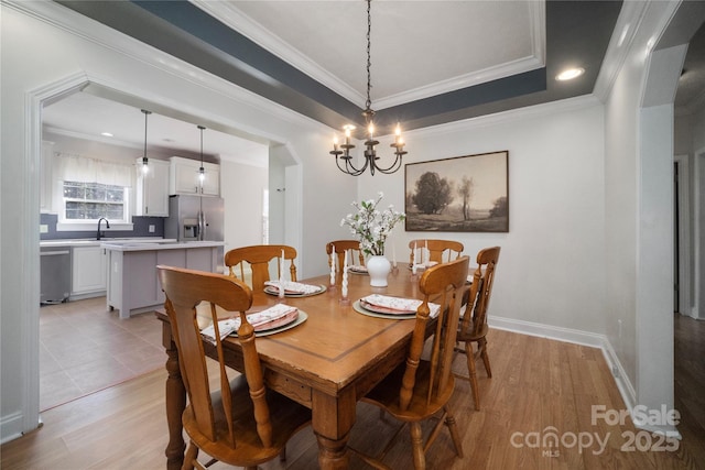 dining space with light wood-type flooring, crown molding, and baseboards