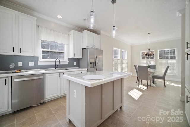 kitchen featuring appliances with stainless steel finishes, a sink, white cabinets, and a center island