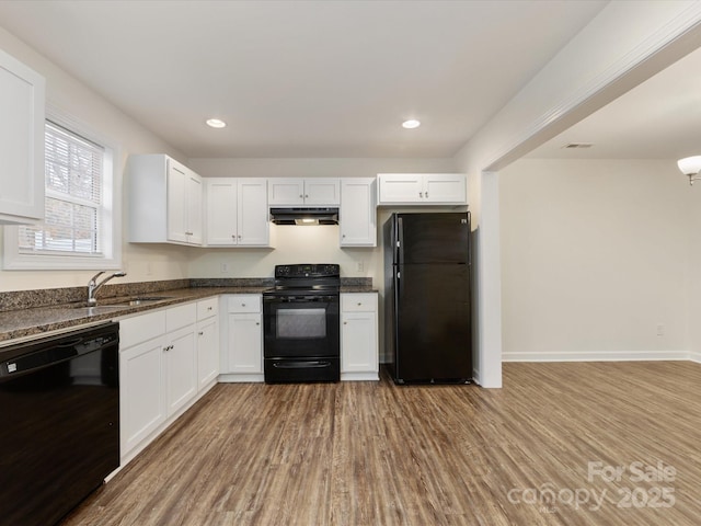 kitchen with white cabinetry, sink, dark stone countertops, light hardwood / wood-style floors, and black appliances