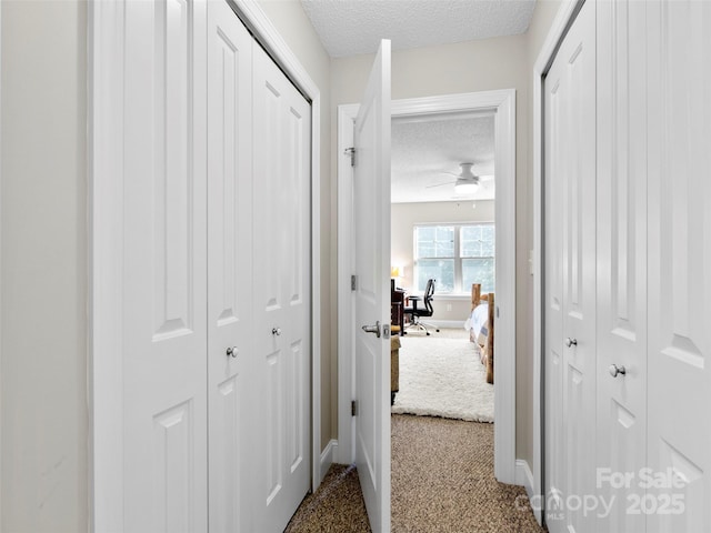 hallway featuring carpet and a textured ceiling