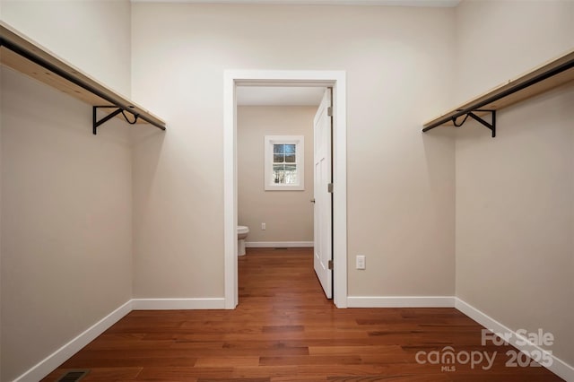 walk in closet with dark wood-type flooring