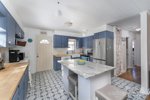 kitchen featuring stainless steel appliances, blue cabinets, a breakfast bar area, and sink