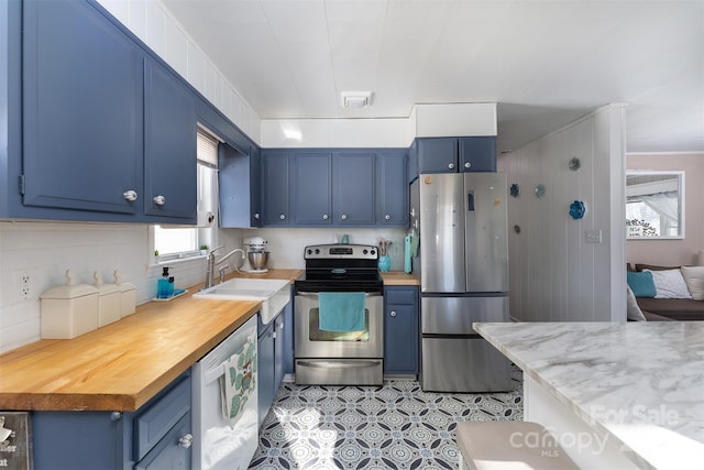 kitchen featuring blue cabinetry, sink, stainless steel appliances, and wooden counters