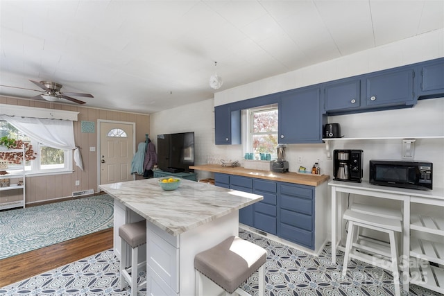 kitchen featuring a kitchen breakfast bar, a wealth of natural light, ceiling fan, and blue cabinets