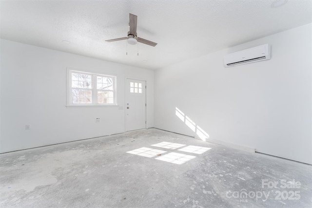 unfurnished room featuring an AC wall unit, ceiling fan, and a textured ceiling