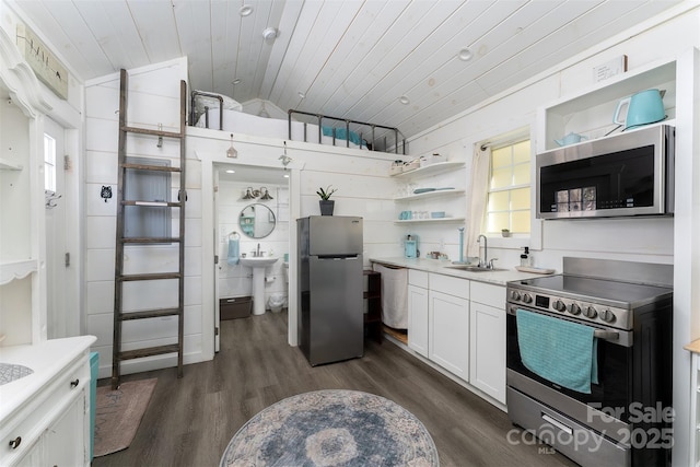 kitchen with wood ceiling, stainless steel appliances, wooden walls, sink, and white cabinetry