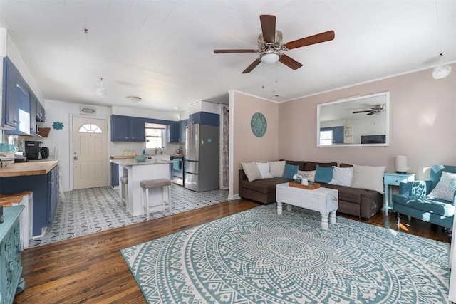 living room with hardwood / wood-style flooring, ceiling fan, ornamental molding, and sink