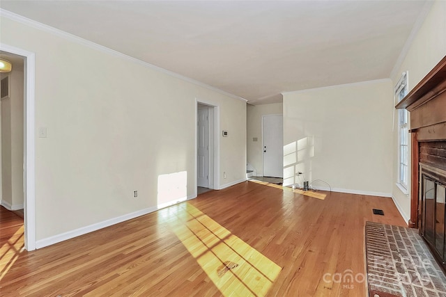 unfurnished living room featuring light hardwood / wood-style flooring, a brick fireplace, and crown molding