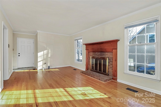 unfurnished living room with ornamental molding, a brick fireplace, and hardwood / wood-style floors