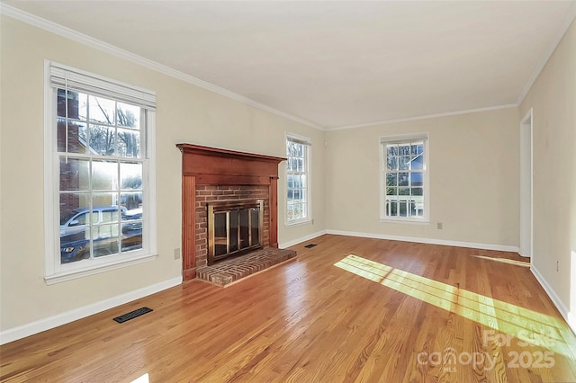 unfurnished living room with a brick fireplace, ornamental molding, and wood-type flooring