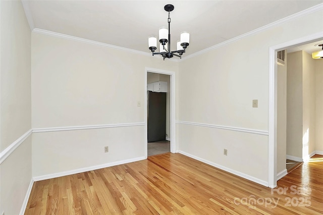 spare room featuring wood-type flooring, a notable chandelier, and crown molding