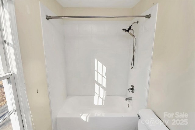 bathroom featuring tiled shower / bath combo and toilet