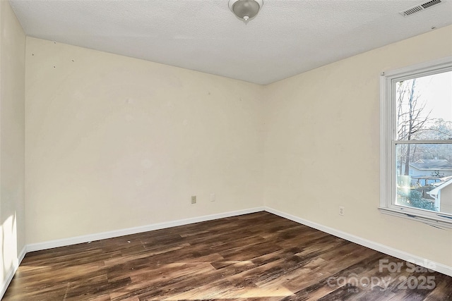 spare room with a textured ceiling and dark hardwood / wood-style floors