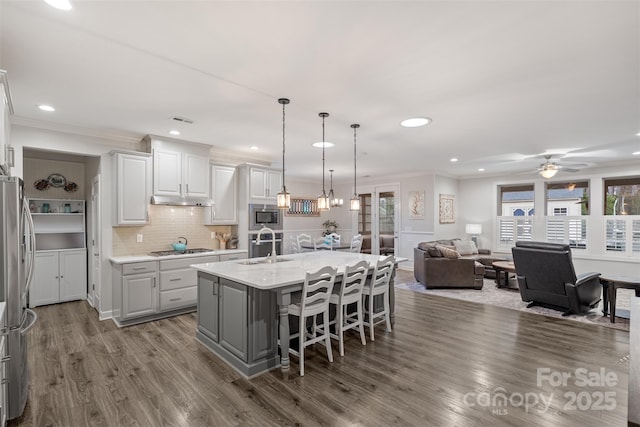 kitchen featuring appliances with stainless steel finishes, decorative light fixtures, sink, a breakfast bar, and a center island with sink