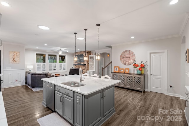 kitchen featuring sink, dark wood-type flooring, gray cabinetry, and an island with sink