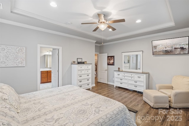 bedroom featuring a tray ceiling, hardwood / wood-style flooring, ceiling fan, ensuite bathroom, and crown molding